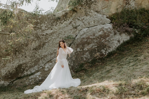 Hermosa novia feliz afuera en un prado de verano al atardecer con una vista perfecta