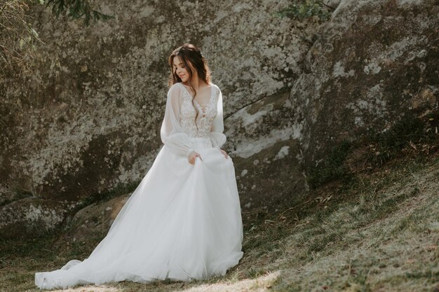 Hermosa novia feliz afuera en un prado de verano al atardecer con una vista perfecta