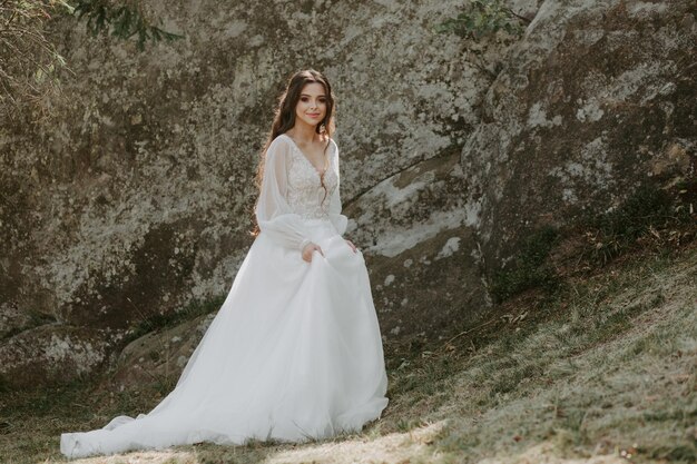 Hermosa novia feliz afuera en un prado de verano al atardecer con una vista perfecta