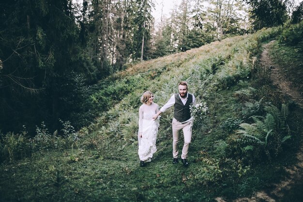 Hermosa novia hermosa posando para el novio y divirtiéndose, ceremonia de lujo en las montañas