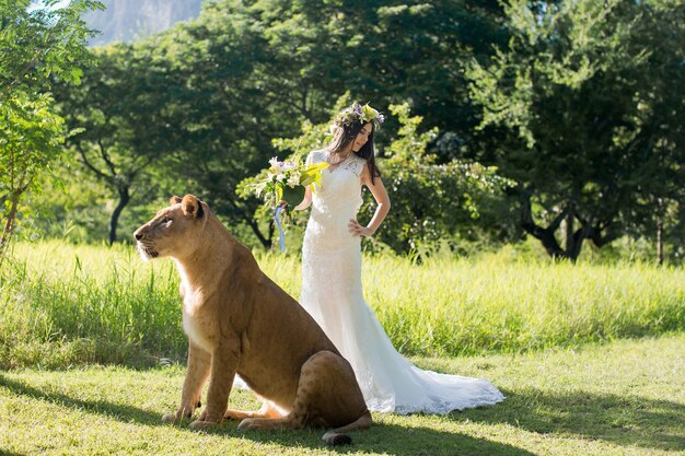 Hermosa novia y una leona en la pintoresca naturaleza.