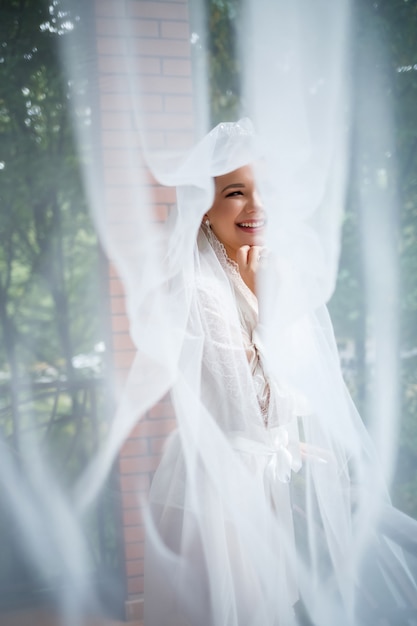 Hermosa novia en una mañana de bodas en albornoz y velo