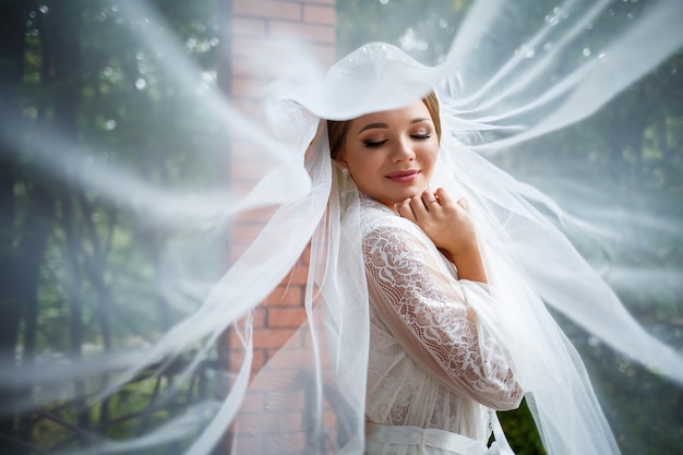 Hermosa novia en una mañana de bodas en albornoz y velo