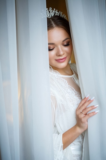 Hermosa novia en una mañana de bodas en albornoz y velo