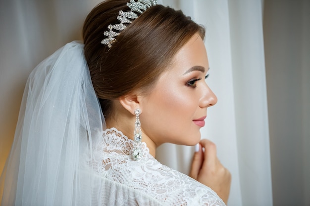 Hermosa novia en una mañana de bodas en albornoz y velo