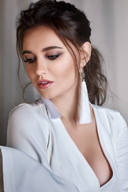 Hermosa novia con maquillaje de moda y peinado en un vestido de novia de lujo