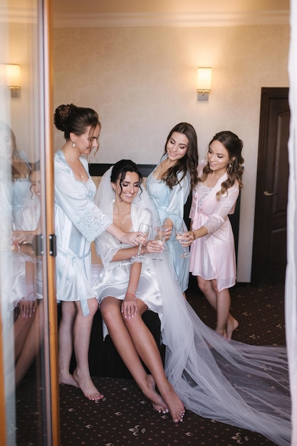 Foto hermosa novia con las mejores damas de honor bebiendo champán en el hotel la mañana de la novia damas de honor sexy en bata emocionante