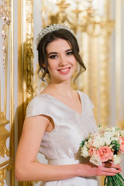 Hermosa novia morena en un lujoso vestido de novia en un rico interior vintage