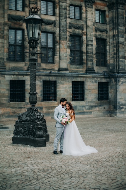 Hermosa novia y el novio abrazándose y besándose en el día de su boda al aire libre