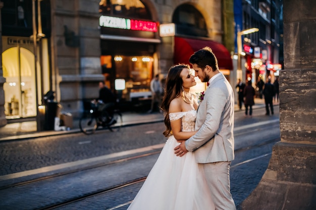 Hermosa novia y el novio abrazándose y besándose en el día de su boda al aire libre