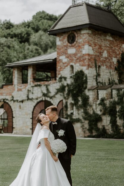 Hermosa novia y el novio abrazándose y besándose en el día de su boda al aire libre