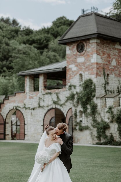 Hermosa novia y el novio abrazándose y besándose en el día de su boda al aire libre