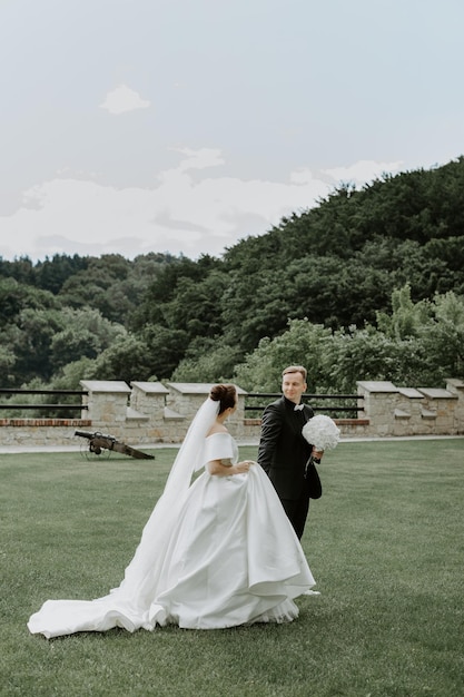 Hermosa novia y el novio abrazándose y besándose en el día de su boda al aire libre