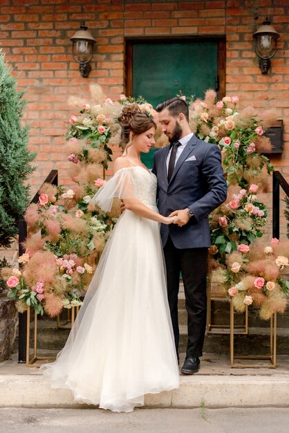 Hermosa novia y el novio cerca de decoraciones florales