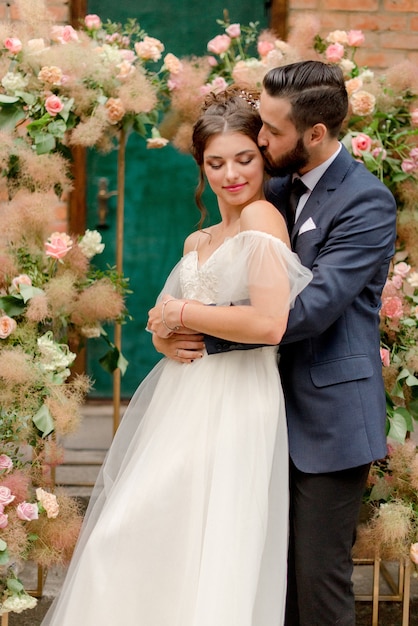 Hermosa novia y el novio cerca de decoraciones florales