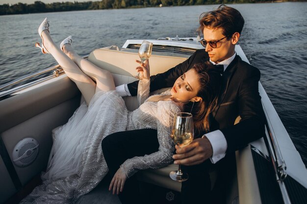 Hermosa novia y novio montan un yate beben vino y disfrutan el momento Día de la boda