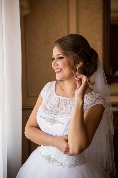 Foto hermosa novia de pie cerca de la ventana y sonriendo