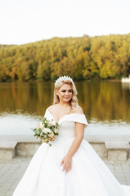 Hermosa novia con un ramo de flores diferentes en el lago de fondo. Boda Rústica.