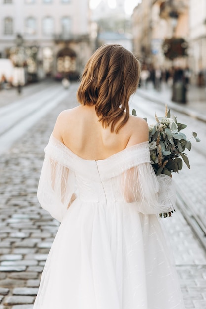 Hermosa novia con un ramo posando en las calles de la ciudad