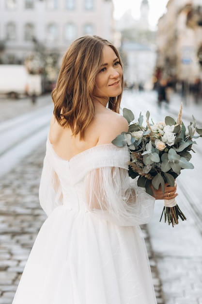 Hermosa novia con un ramo posando en las calles de la ciudad