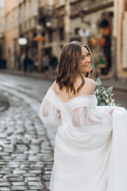 Hermosa novia con un ramo posando en las calles de la ciudad