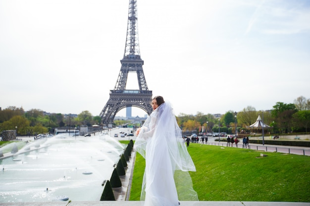 Hermosa novia con un rico vestido de novia gira en la plaza ante la Torre Eiffel