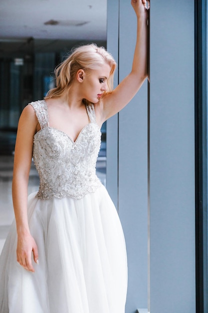 Hermosa novia rubia con el pelo corto y un vestido blanco hinchado posando para la cámara