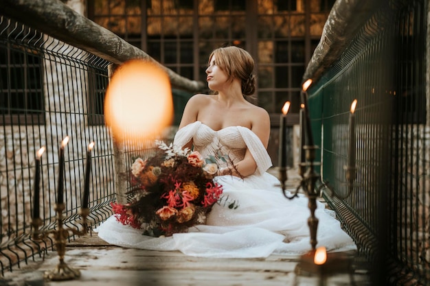 Foto hermosa novia sentada en un puente de madera lleno de velas