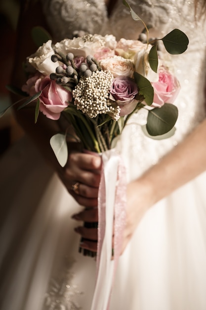 Hermosa novia sosteniendo un delicado ramo de flores en sus manos en el día de la boda