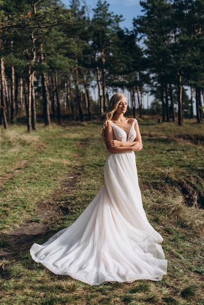 una hermosa novia con un vestido blanco se encuentra en la cima de una montaña