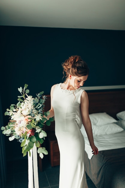 Hermosa novia con un vestido de encaje blanco con un ramo de flores está dando la vuelta y mirando