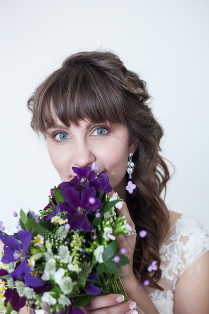 Hermosa novia en vestido de encaje blanco con un ramo de flores