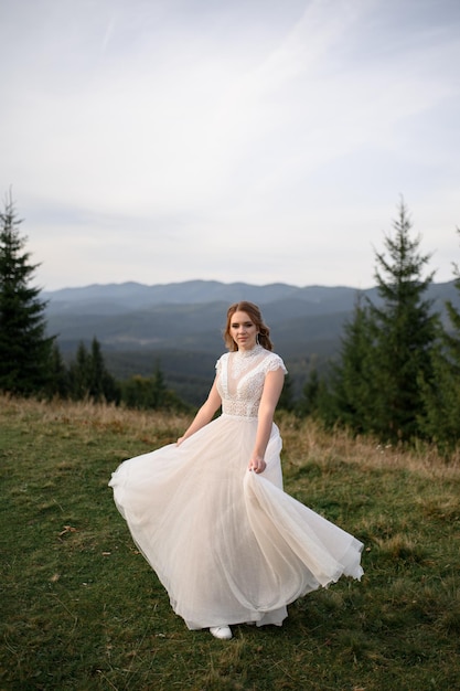 Hermosa novia con un vestido de novia blanco sobre un fondo de montañas