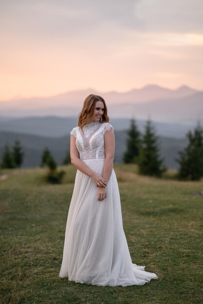 Hermosa novia con un vestido de novia blanco sobre un fondo de montañas