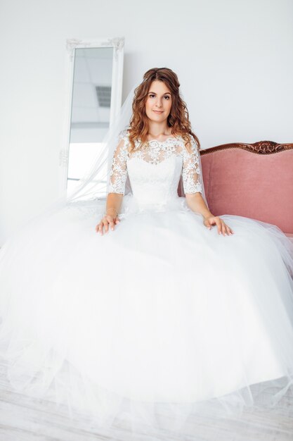 Hermosa novia en un vestido de novia con encaje, posando en el estudio