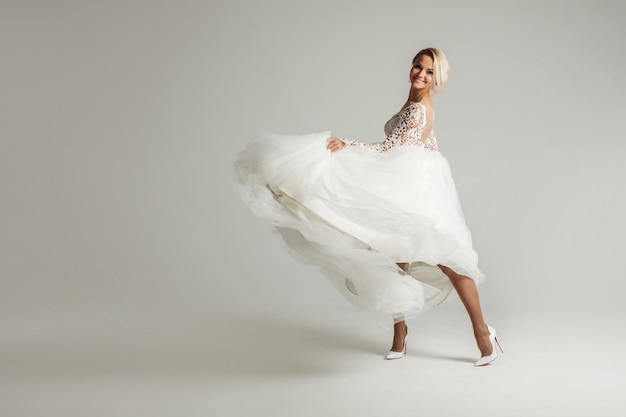 Hermosa novia en vestido de novia con falda larga completa en blanco