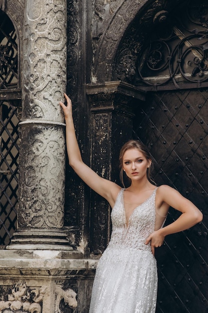 Hermosa novia con vestido de novia de lujo está parada frente a un edificio