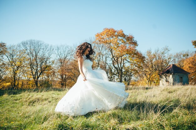 hermosa novia en un vestido de novia en el parque de otoño