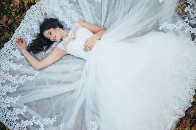 hermosa novia en un vestido de novia en el parque de otoño