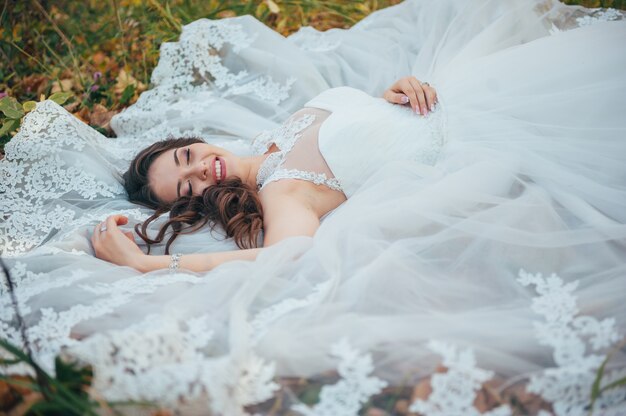 hermosa novia en un vestido de novia en el parque de otoño