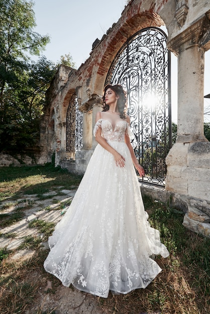 Hermosa novia en vestido de novia, que se fotografía en el día de la boda cerca del antiguo castillo.