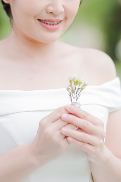 Hermosa novia en vestido de novia sonrió feliz y sosteniendo lindas flores