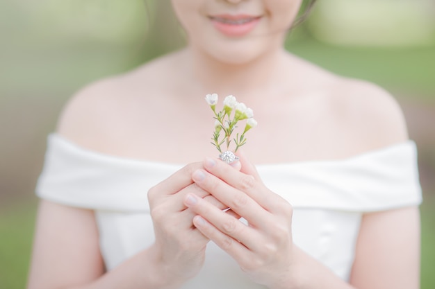 Hermosa novia en vestido de novia sonrió feliz y sosteniendo lindas flores