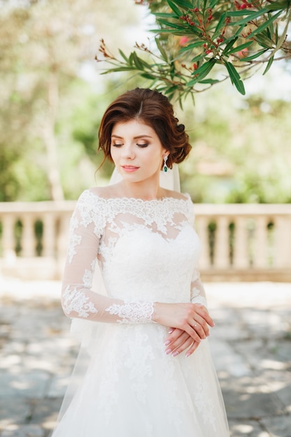 Hermosa novia en vestido de novia tierno con ramo de novia en las escaleras de la iglesia