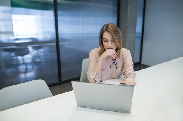 Una hermosa oficinista está mirando la computadora al final.