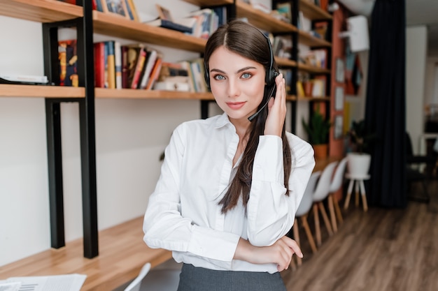 Hermosa operadora de call center que responde a clientes con auriculares