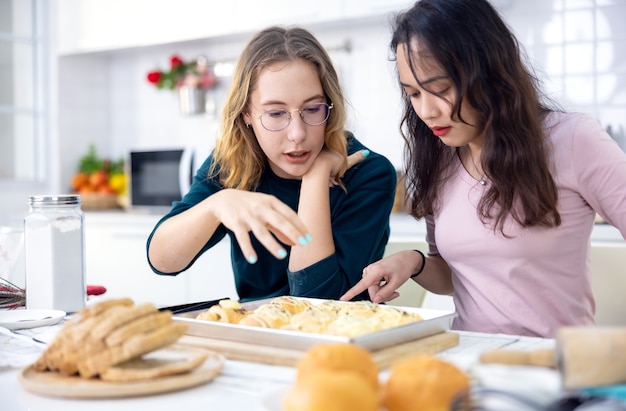 Hermosa panadera haciendo pasteles, lindas y felices dos mujeres se divierten en un aula de preparación de pan y usan sus manos para juntar la masa para hacer pasteles en la cocina de casa.