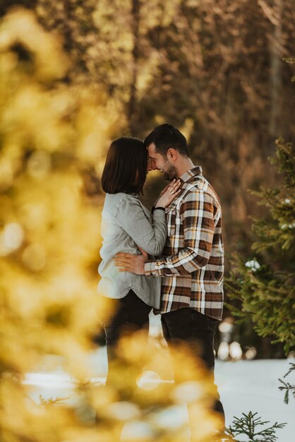 Hermosa pareja abrazándose entre pinos nevados mujer en ropa casual cogidos de la mano en el pecho del hombre Enfoque selectivo