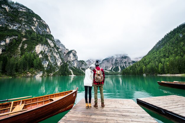 Hermosa pareja de adultos jóvenes visitando un lago alpino en Braies Italia