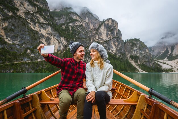 Hermosa pareja de adultos jóvenes visitando un lago alpino en Braies Italia